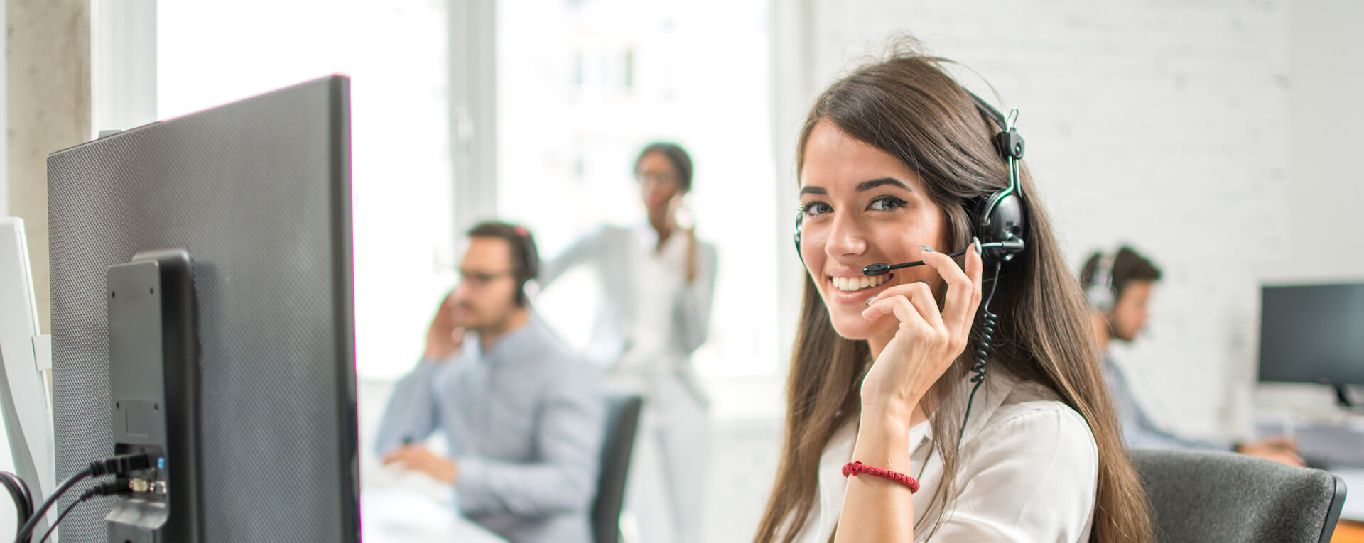 Mitarbeiterin des deutschen bKV Service sitzt mit Headset zum telefonieren vor einem Bildschirm.